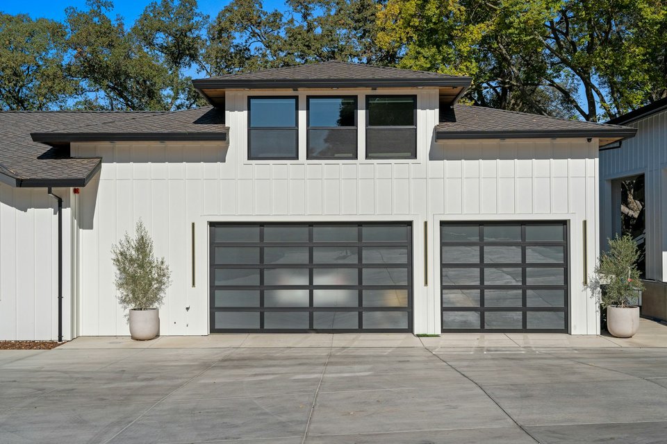 Maison contemporaine avec portes de garage modernes sous ciel bleu — fermeture résidentielle FERMIS
