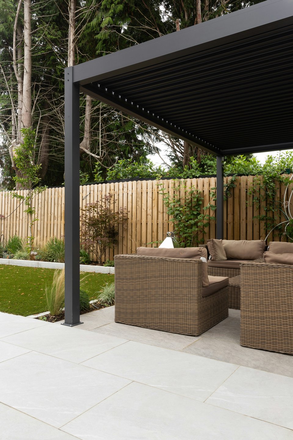 Pergola bioclimatique anthracite à lames aluminium au-dessus d'un salon de jardin