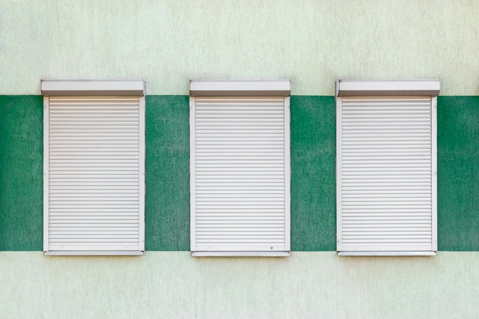 Trois volets roulants blancs sur façade résidentielle moderne